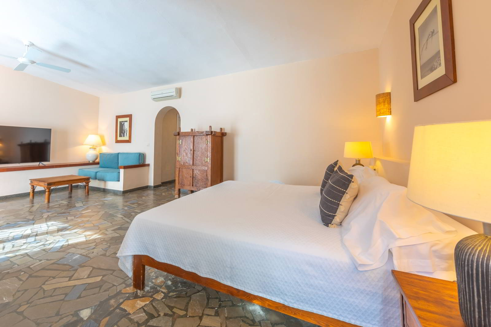 Dormitorio amplio de habitación familiar con cama doble, zona de estar al fondo, iluminación suave y ambiente tranquilo.