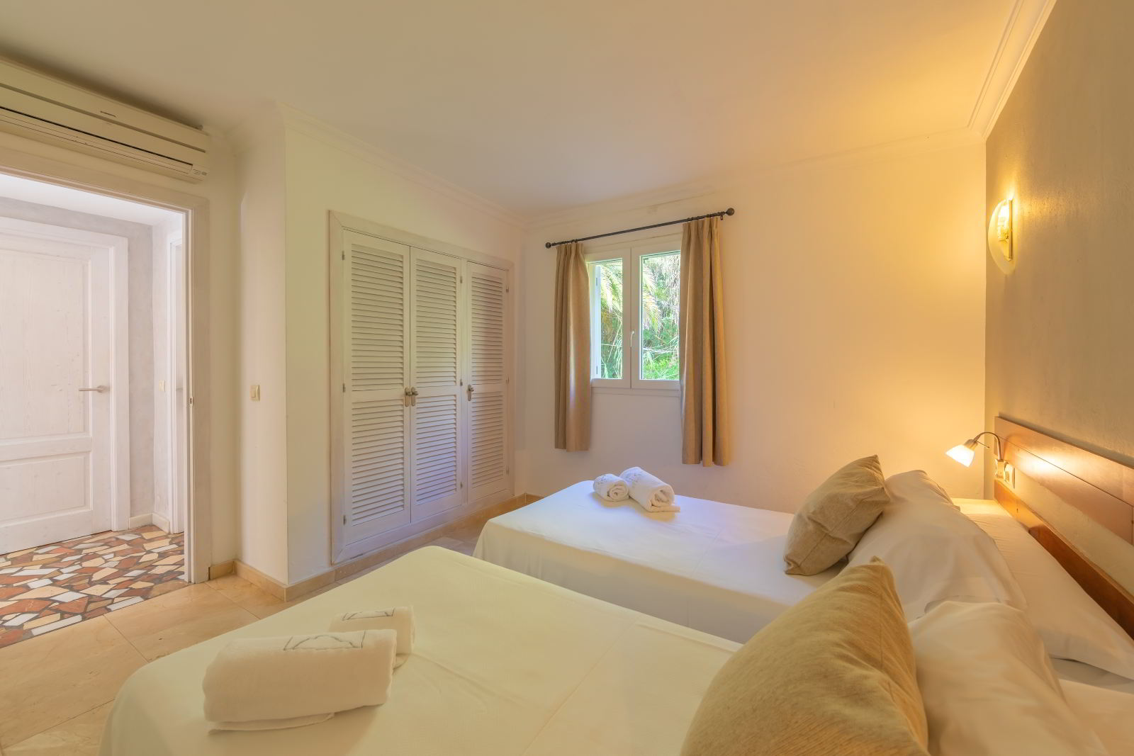 Dormitorio secundario de habitación familiar con dos camas individuales, armario empotrado y luz natural en Hotel Punta Sur.