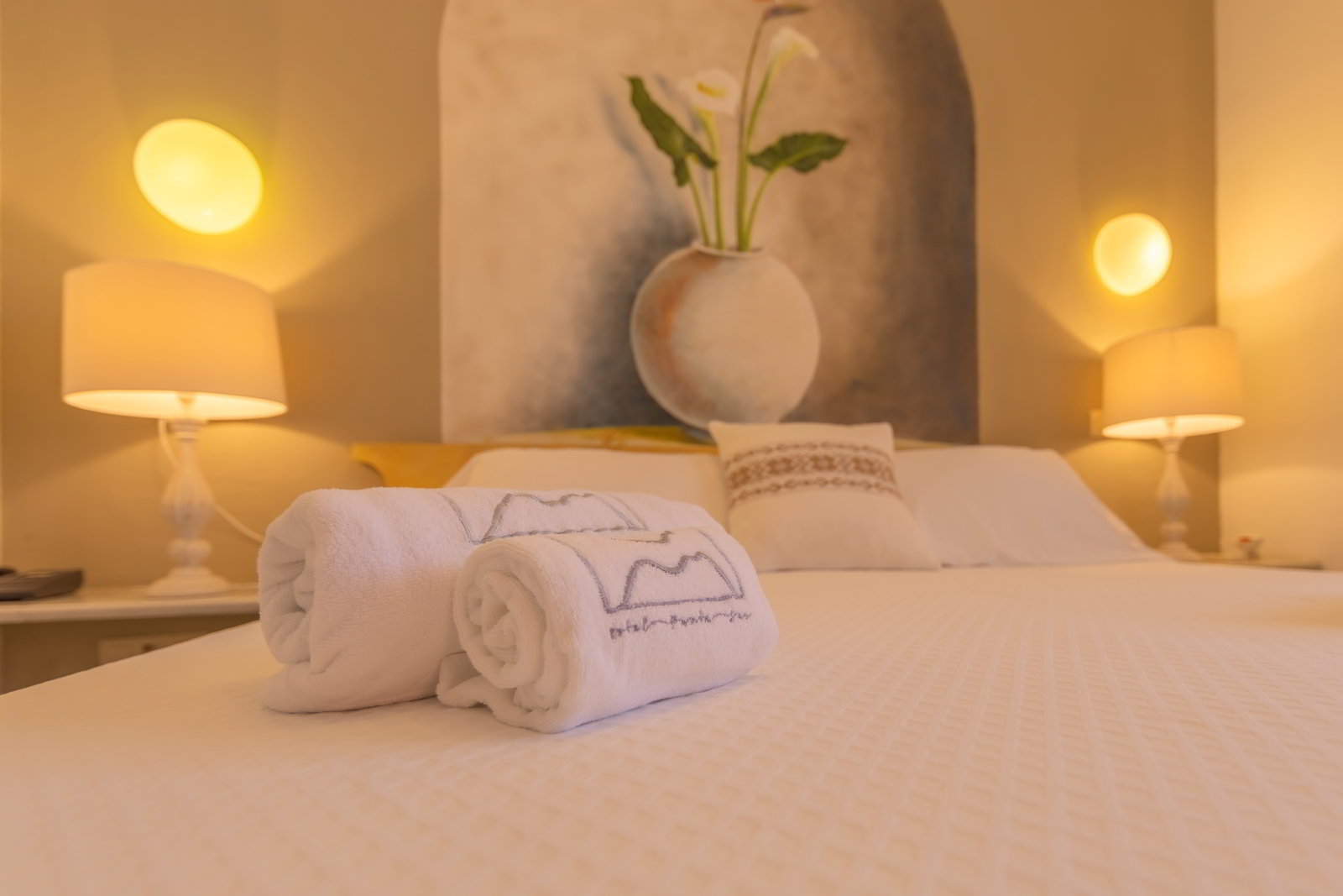 Detalle de la cama con toallas dobladas y luz cálida en la habitación familiar grande del hotel.