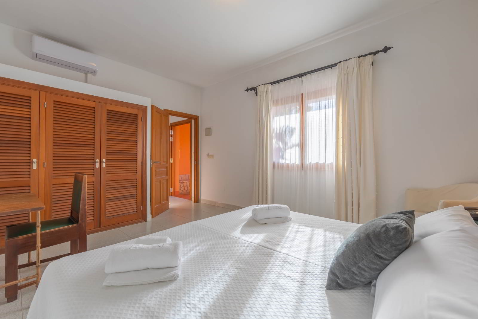 Dormitorio amplio con cama doble, armario empotrado y luz natural en la habitación familiar grande del hotel.