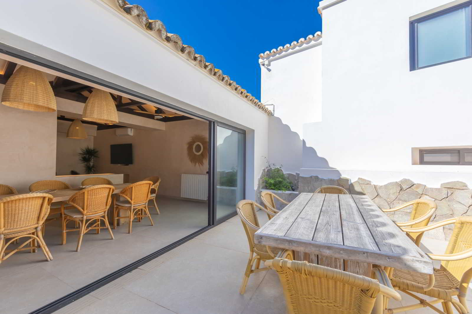 Comedor exterior con mesa de madera rústica y sillas de mimbre en La Villa del Hotel Punta Sur.
