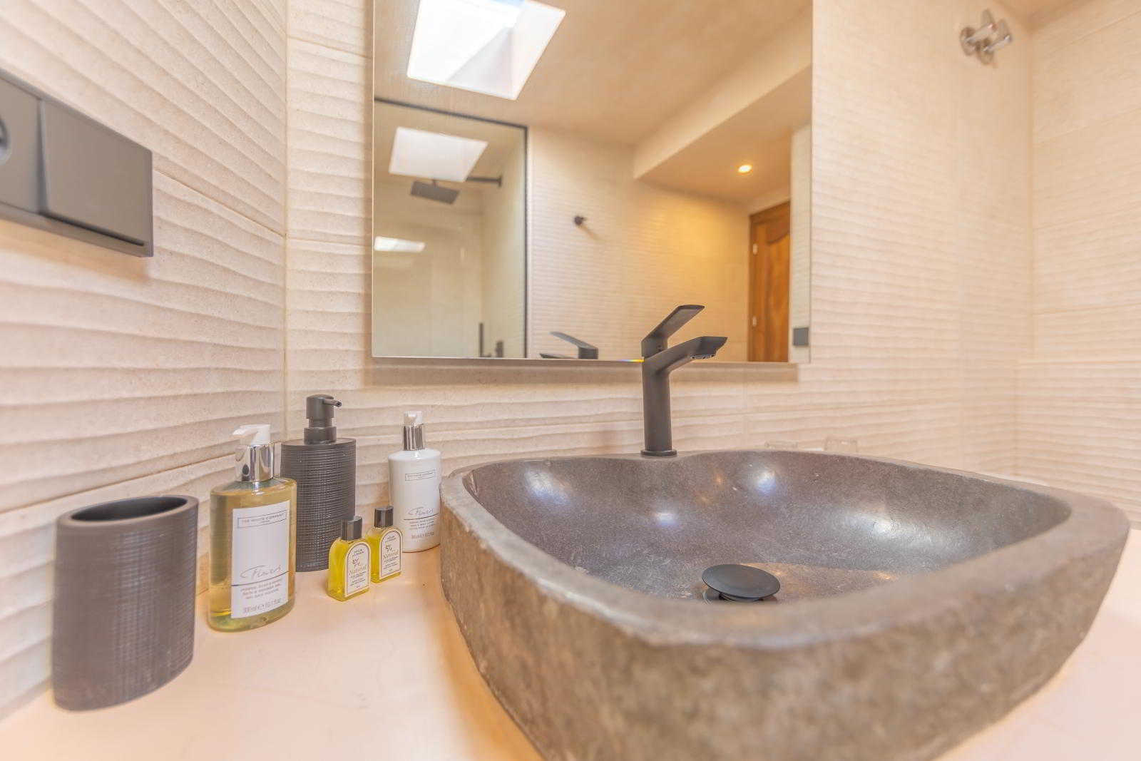 Detalle de lavabo de piedra con grifo negro mate y amenities de baño en La Villa del Hotel Punta Sur.
