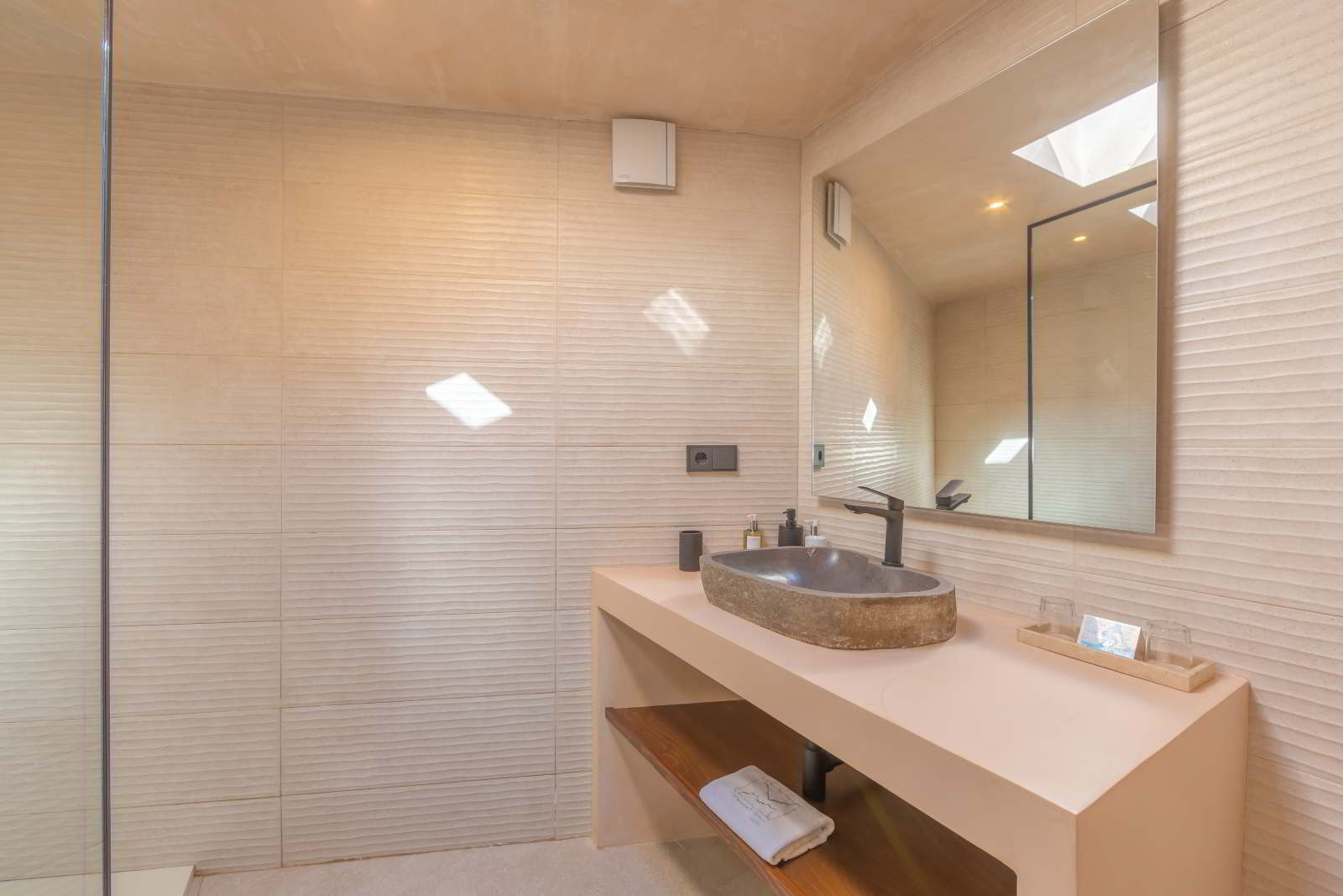 Detalle de lavabo de piedra con grifo negro mate y amenities de baño en La Villa del Hotel Punta Sur.