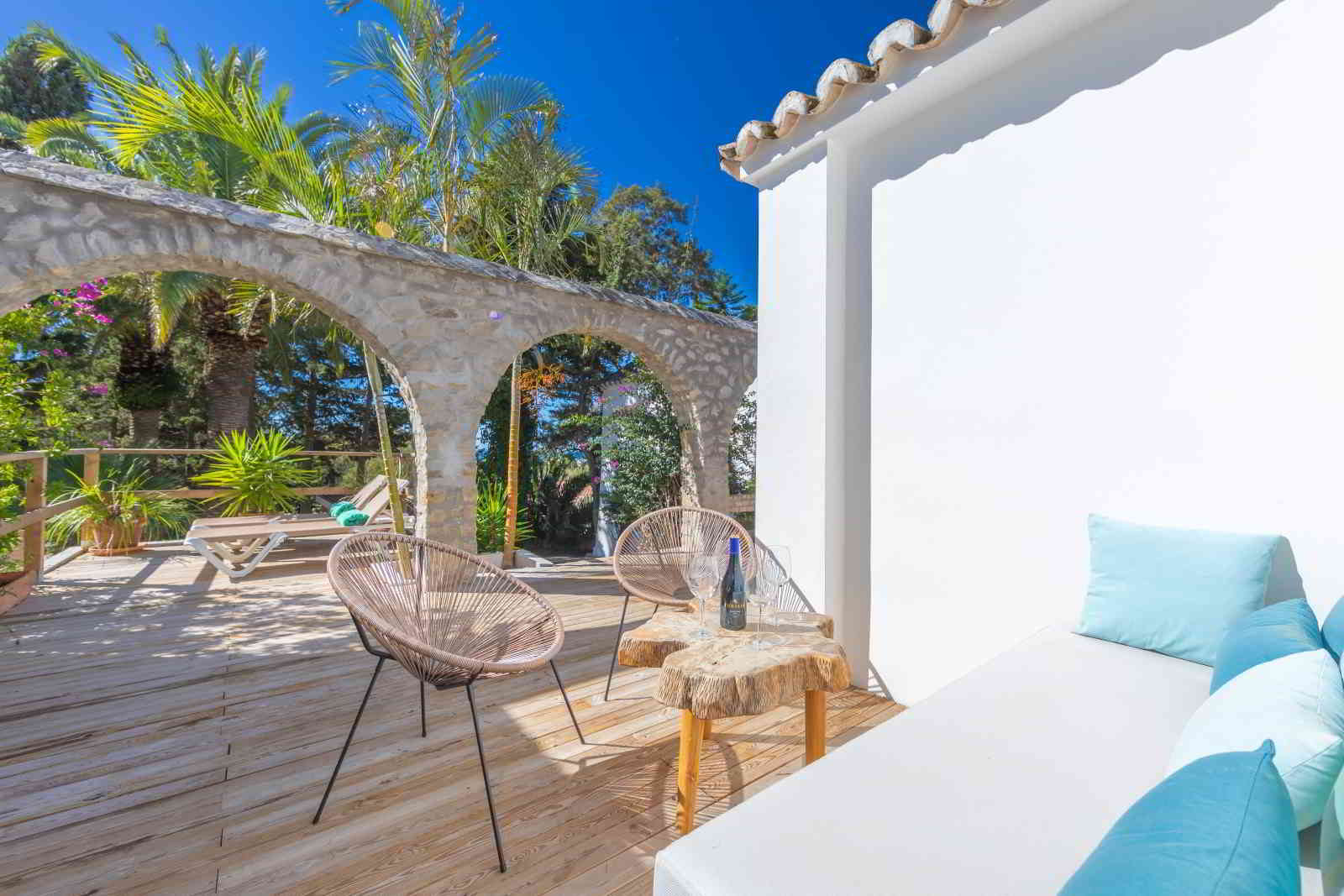 Terraza de La Villa en Hotel Punta Sur con sofá, sillas de diseño, mesa rústica y vistas a los arcos de piedra entre vegetación tropical.