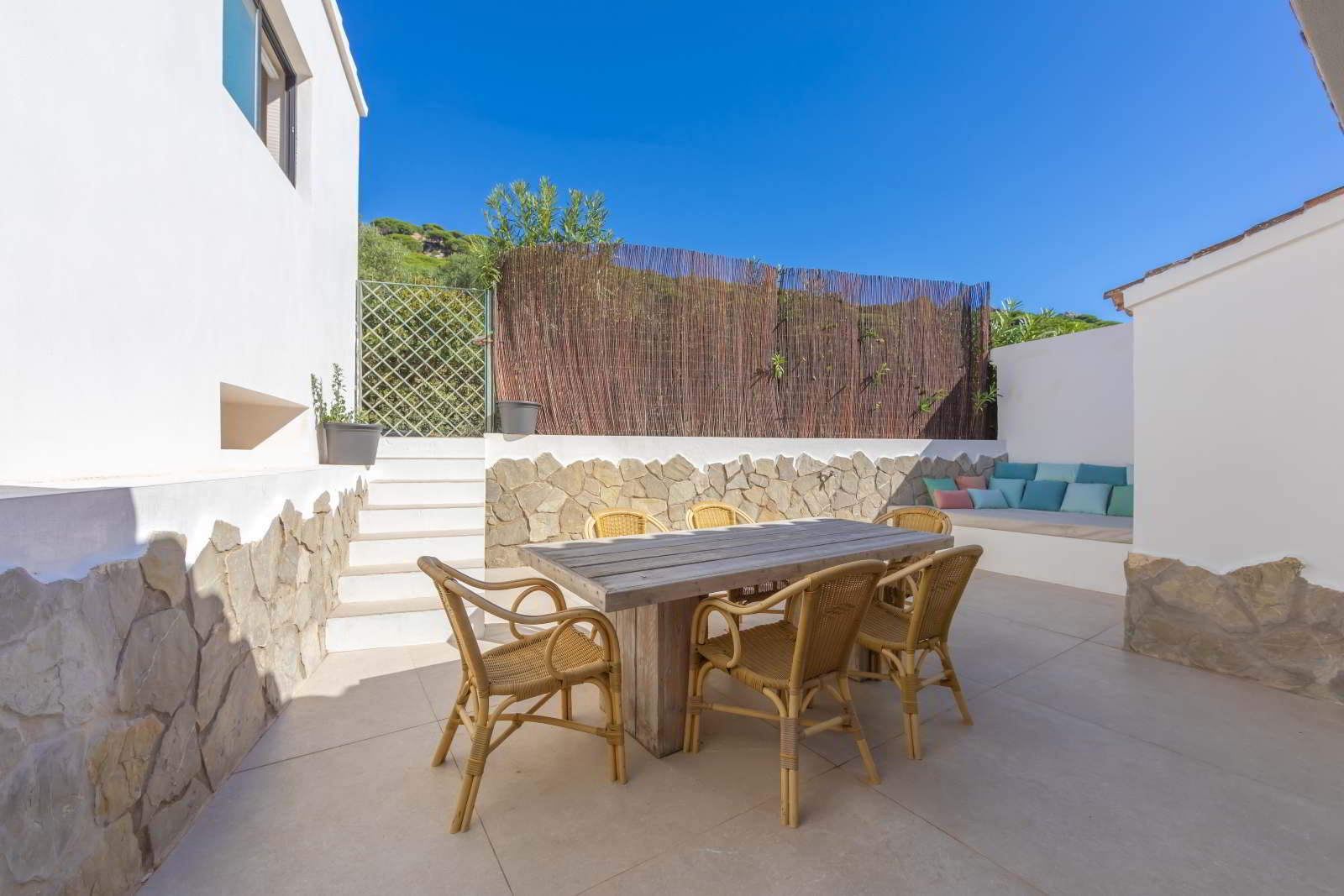 Terraza exterior de La Villa del Hotel Punta Sur con mesa de comedor de madera y banco empotrado con cojines.