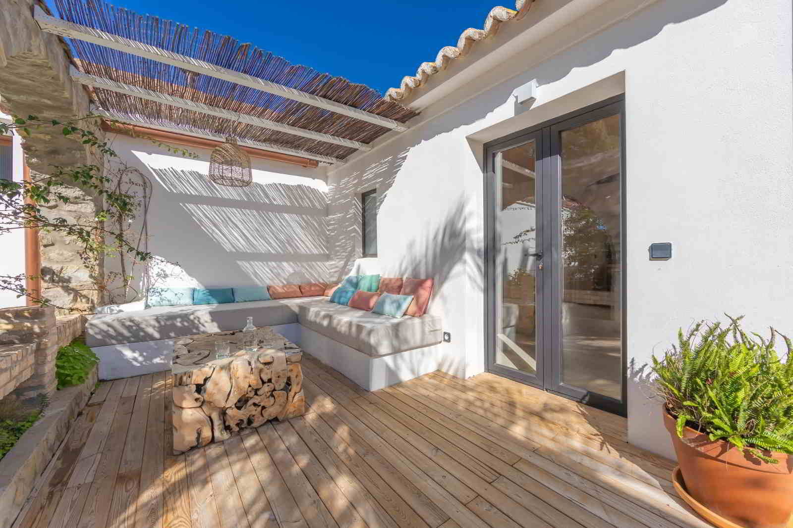 Terraza con pérgola de cañizo y sofá esquinero en La Villa del Hotel Punta Sur, decorada con cojines y mesa de madera orgánica.