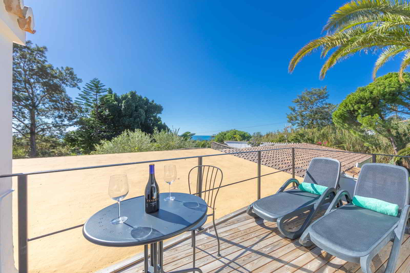 Terraza elevada de La Villa en Hotel Punta Sur con vistas al mar, dos tumbonas y una mesa con vino y copas.