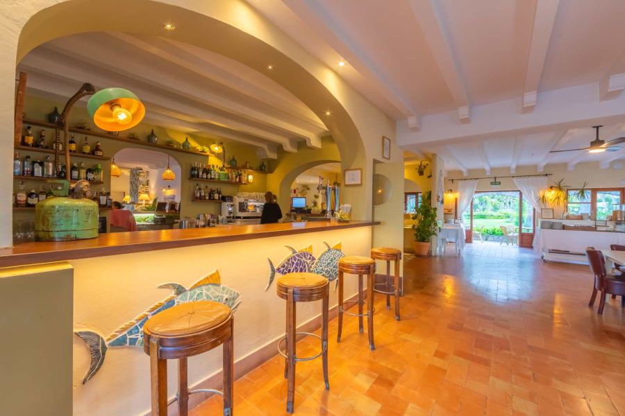 Barra de bar interior en el restaurante del Hotel Punta Sur, con taburetes y decoración de peces.