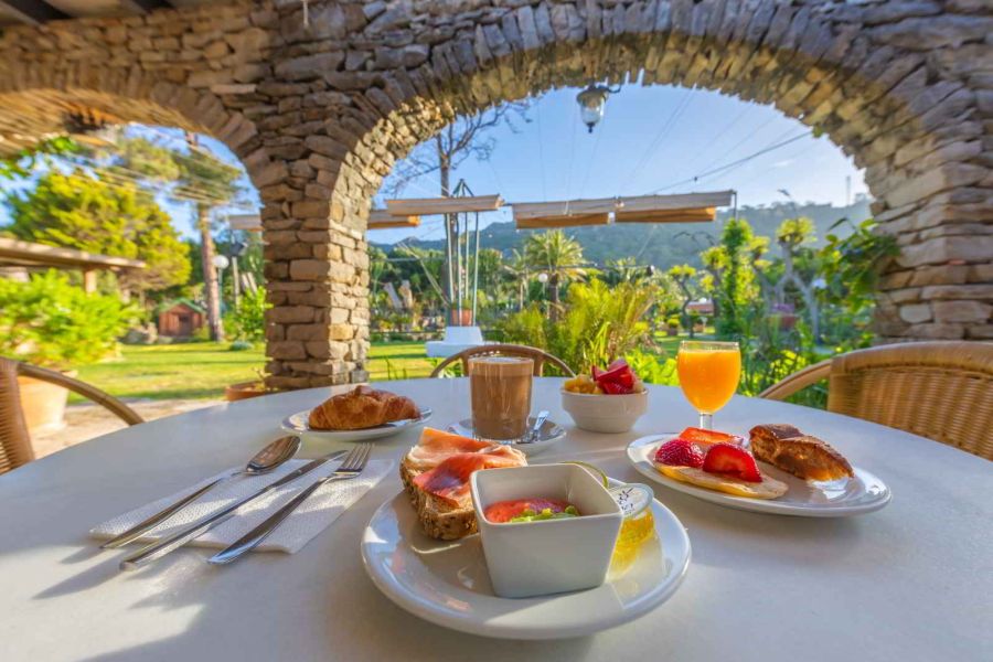 Desayuno servido en mesa exterior bajo un porche de piedra con vistas al jardín del Hotel Punta Sur.