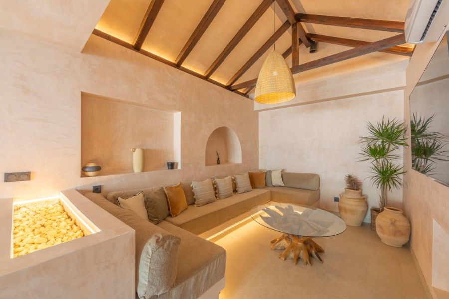 Salón abierto y luminoso de La Villa del Hotel Punta Sur con sofá esquinero y techo de madera.