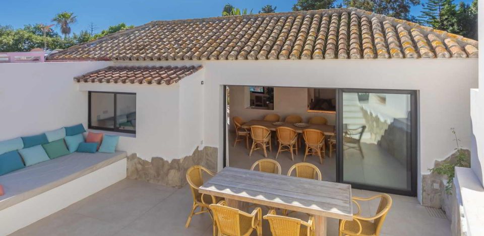 Terraza de La Villa del Hotel Punta Sur con sofá integrado, mesa de comedor y acceso al salón.