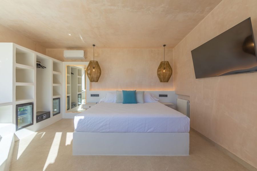 enDormitorio con cama doble, lámparas colgantes de fibras, televisor y espacio de almacenaje en La Villa del Hotel Punta Sur.